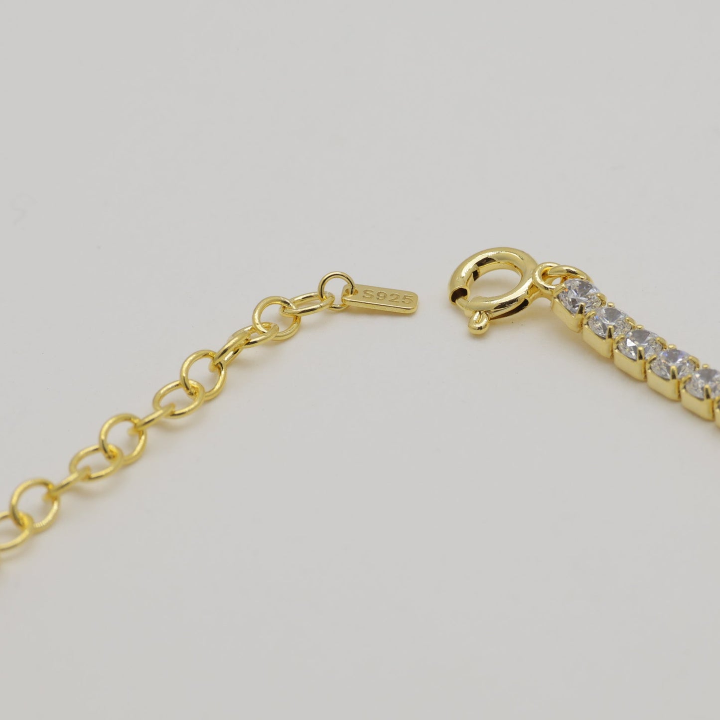 Gold bracelet with clear stones on a light gray background