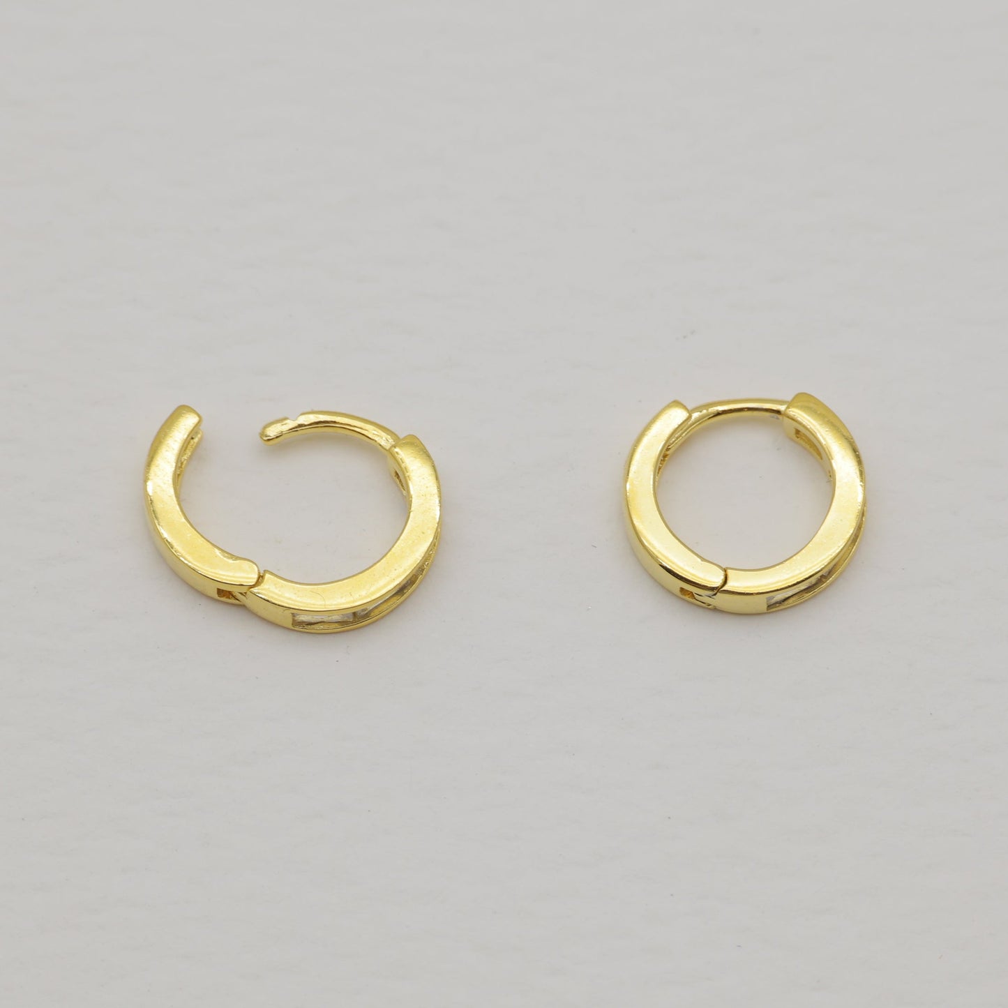 Pair of gold hoop earrings on a light gray background