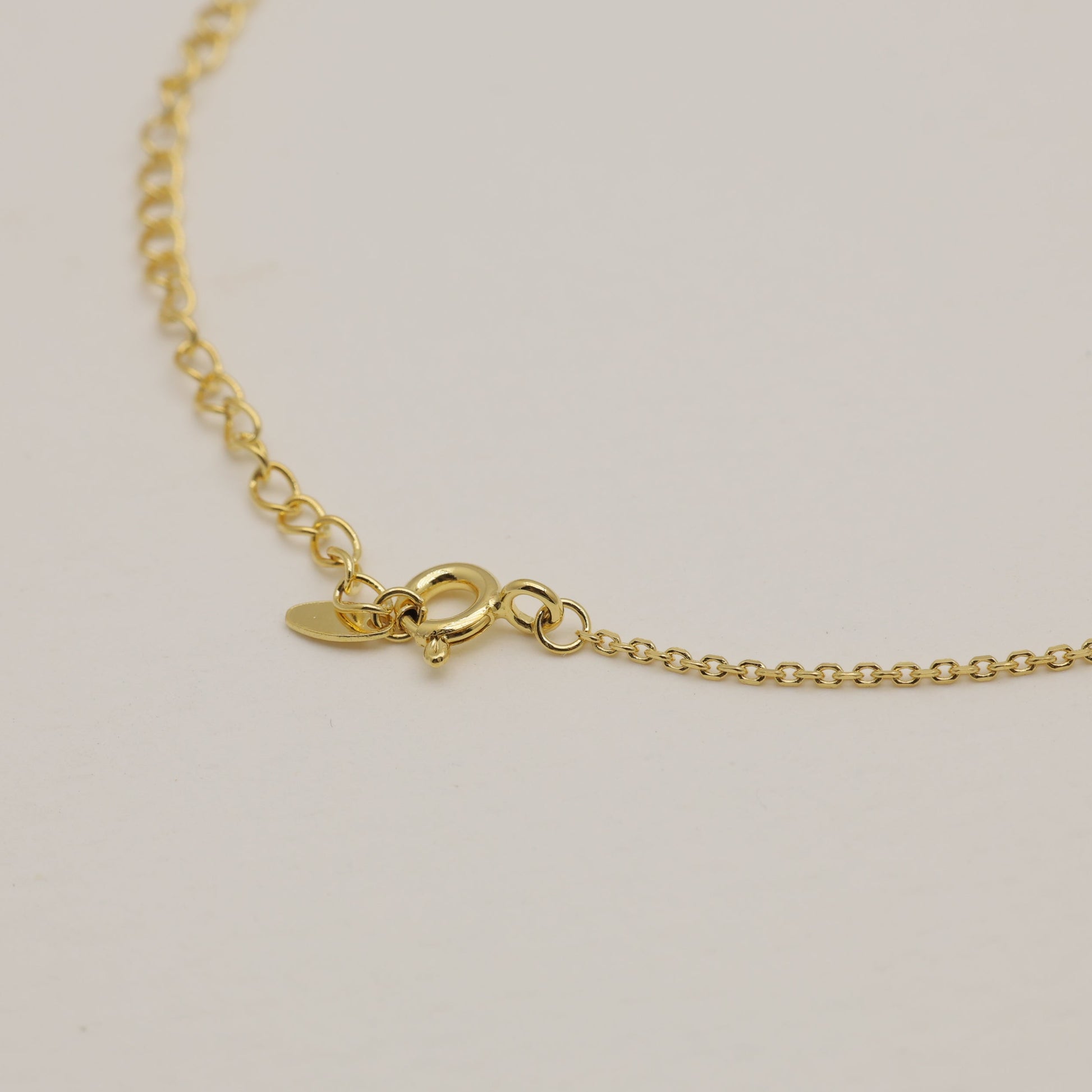 Gold necklace on a light beige background