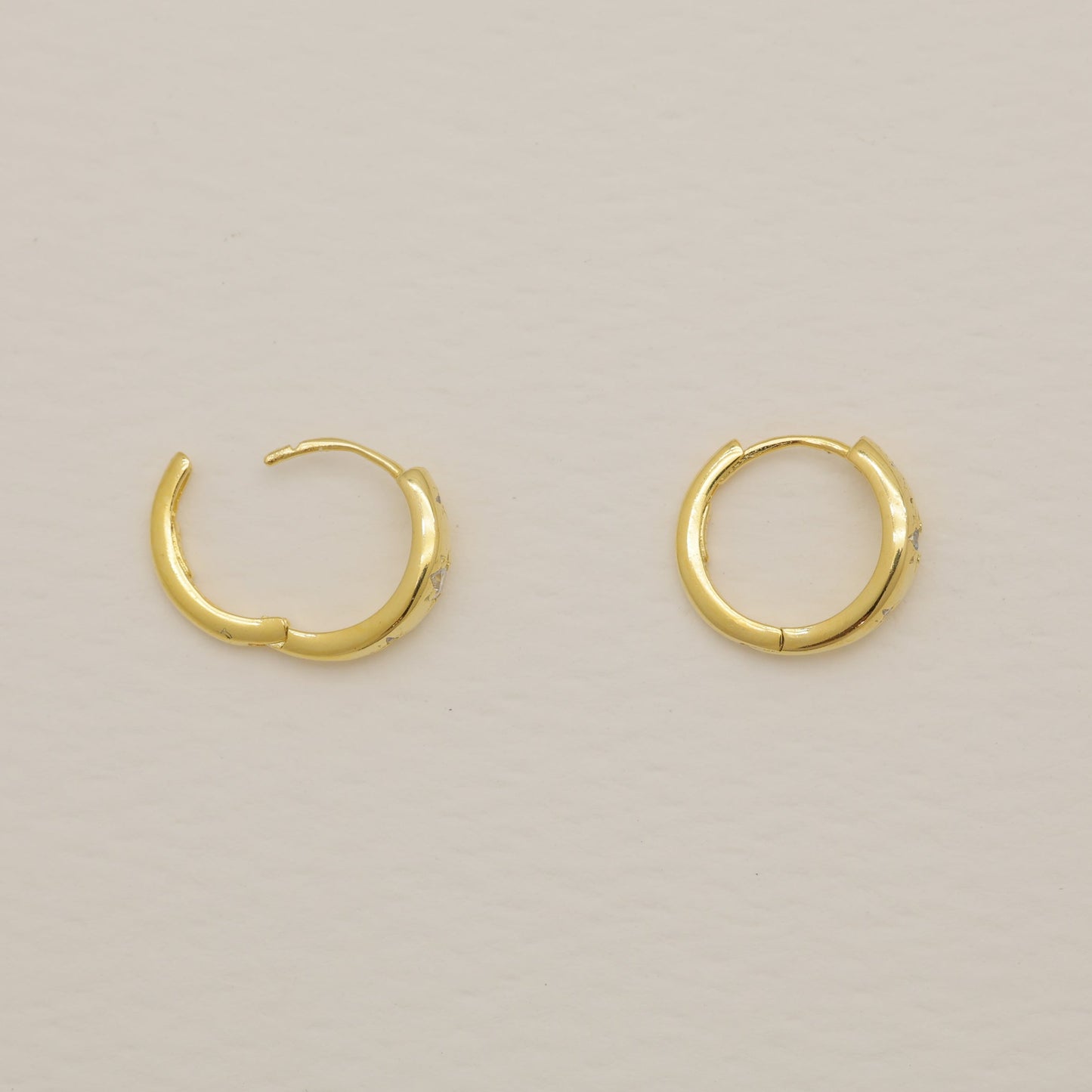 Pair of gold hoop earrings on a light beige background