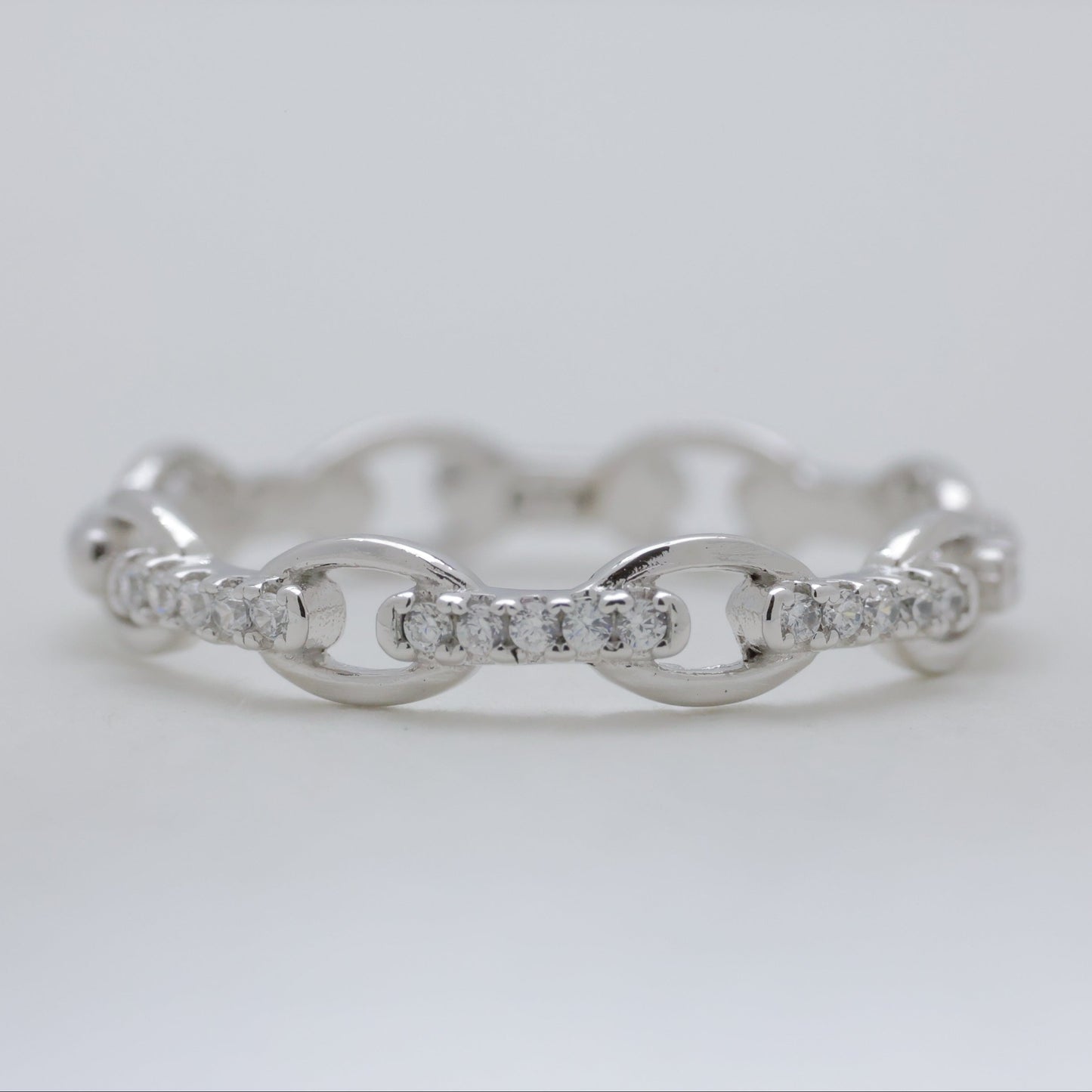 Silver ring with diamond accents on a light gray background