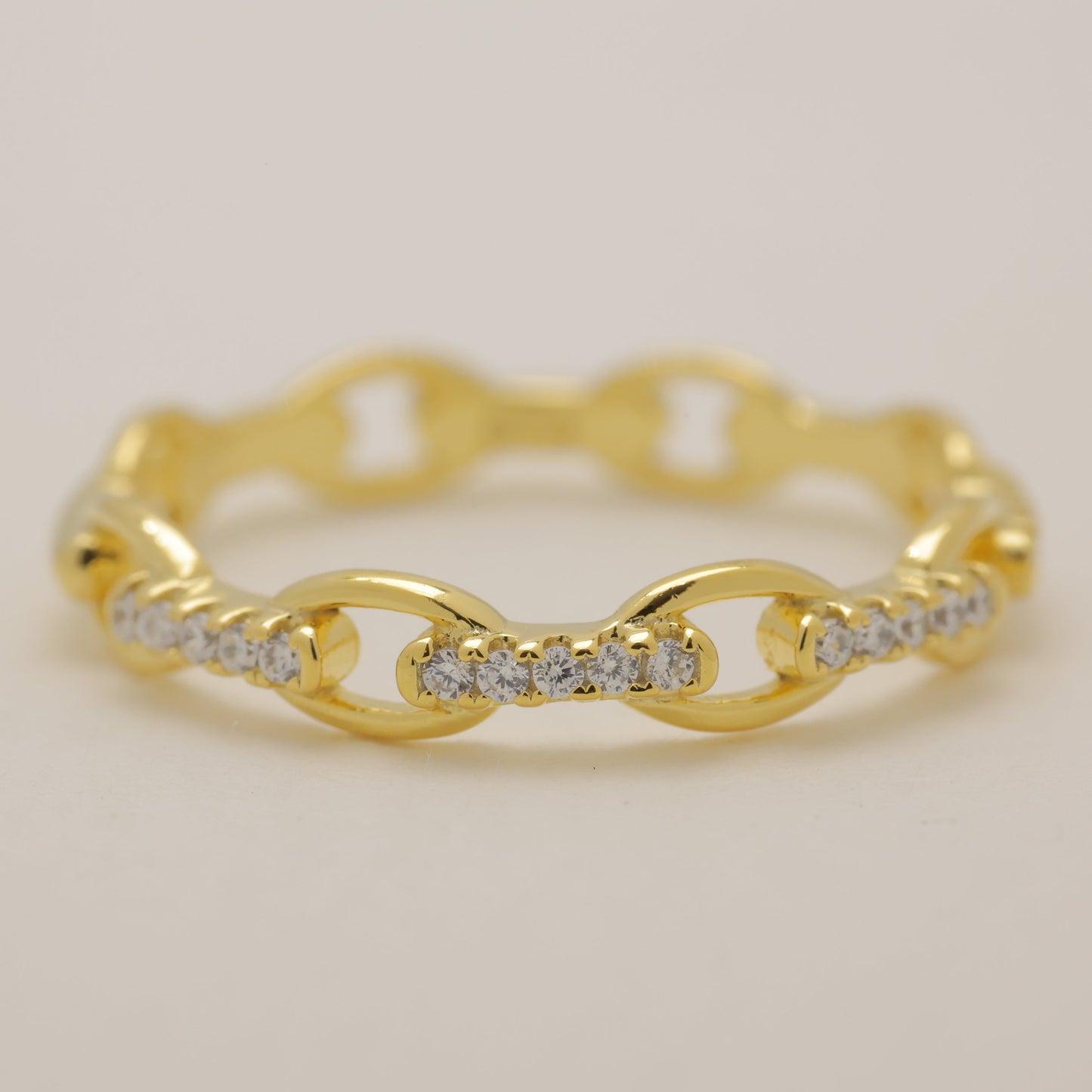 Gold ring with diamond accents on a light beige background