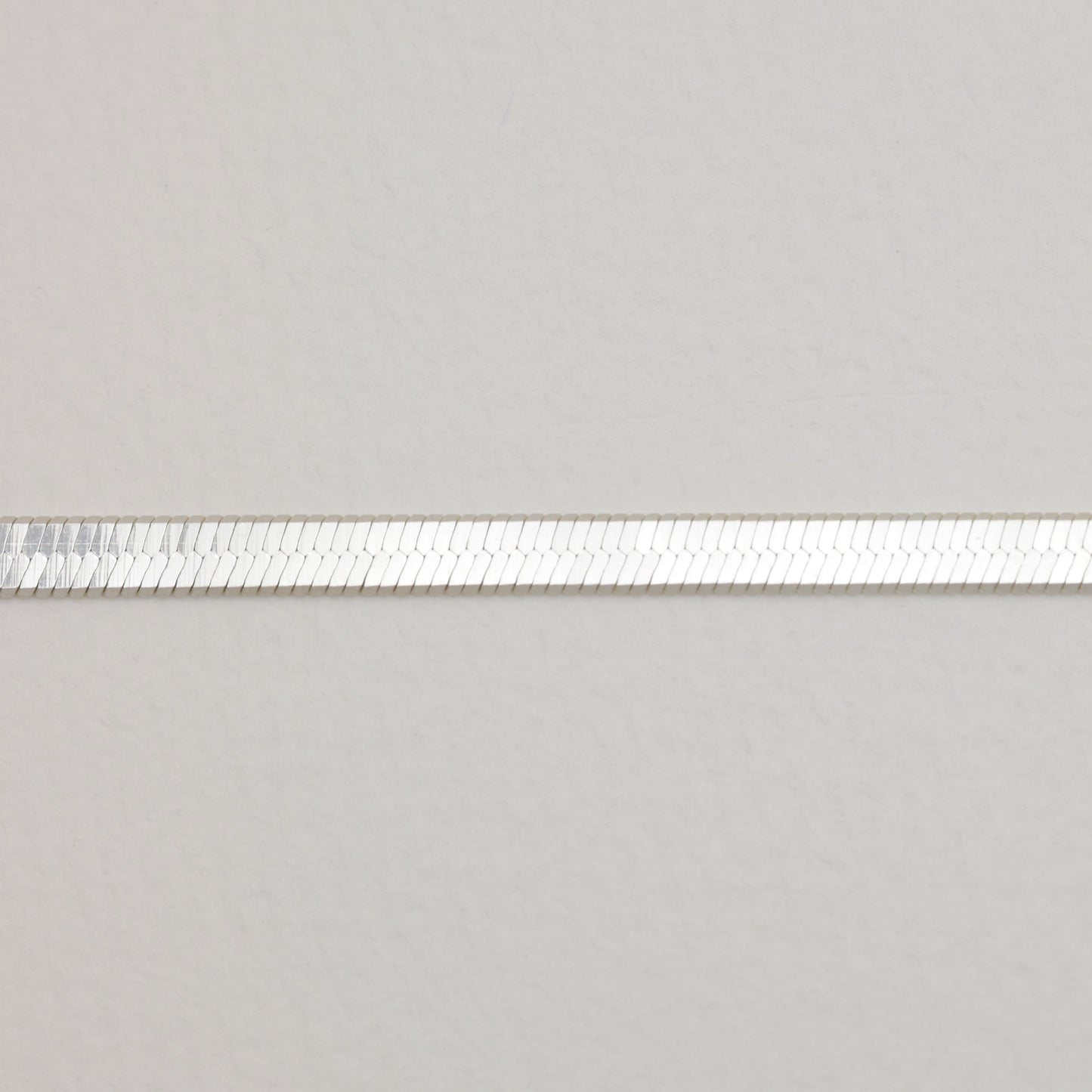 Zoomed view of the smooth, flat silver links in the herringbone chain design