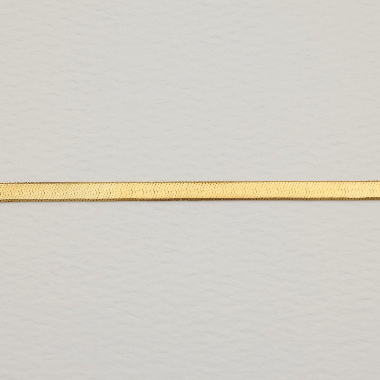 Detail of the fluid herringbone pattern on polished gold vermeil necklace