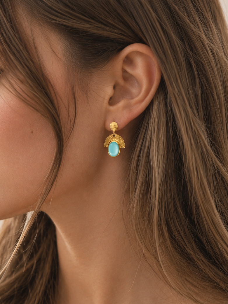 Close-up of a woman wearing gold earrings with turquoise stones.