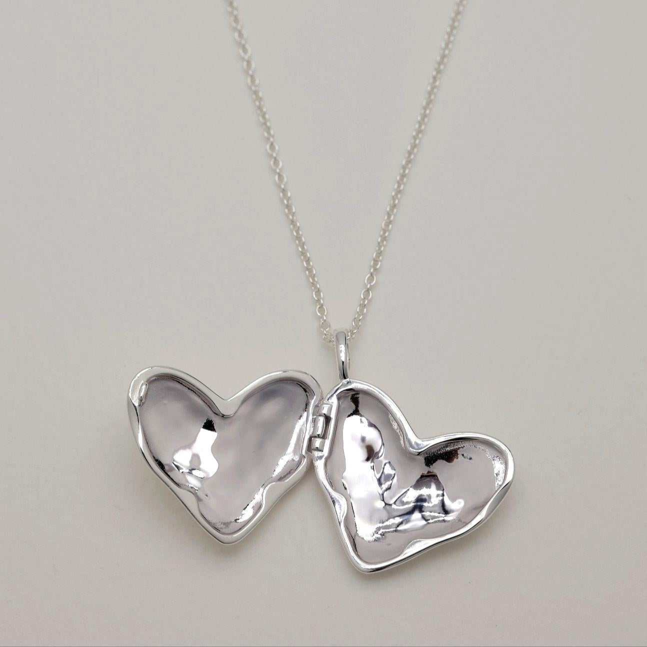 Open heart-shaped locket on a silver chain, showing smooth mirrored interior surfaces.