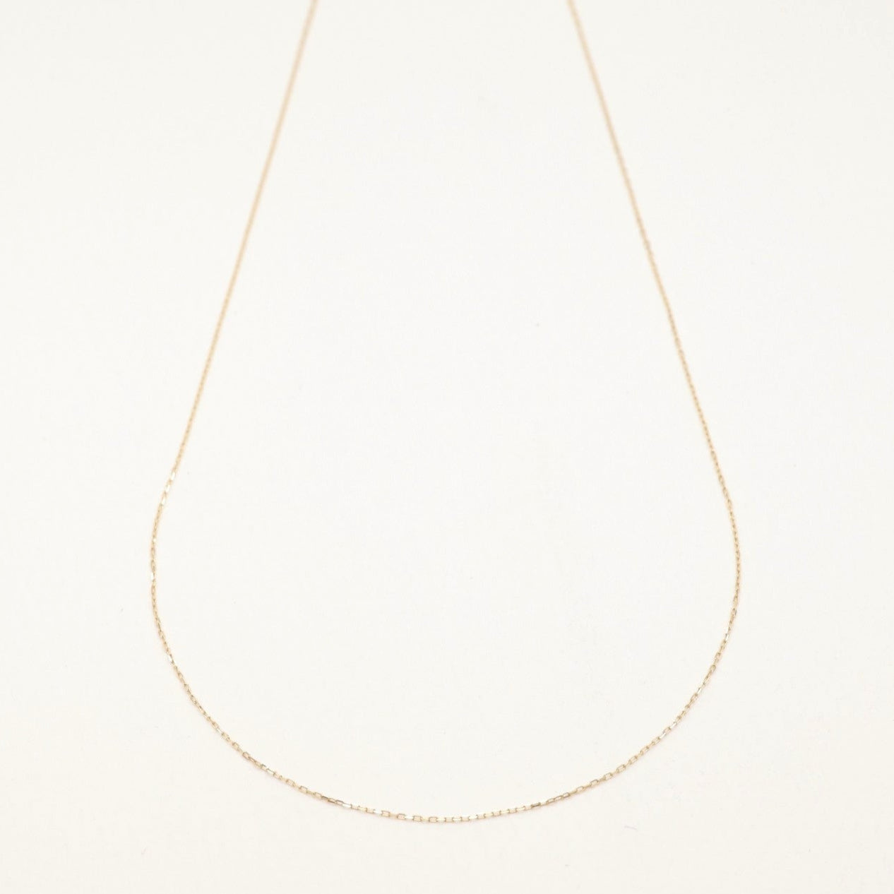 A full view of the Édith Petite Chain Necklace in 10K gold laid flat, capturing its subtle shine and elegant length.