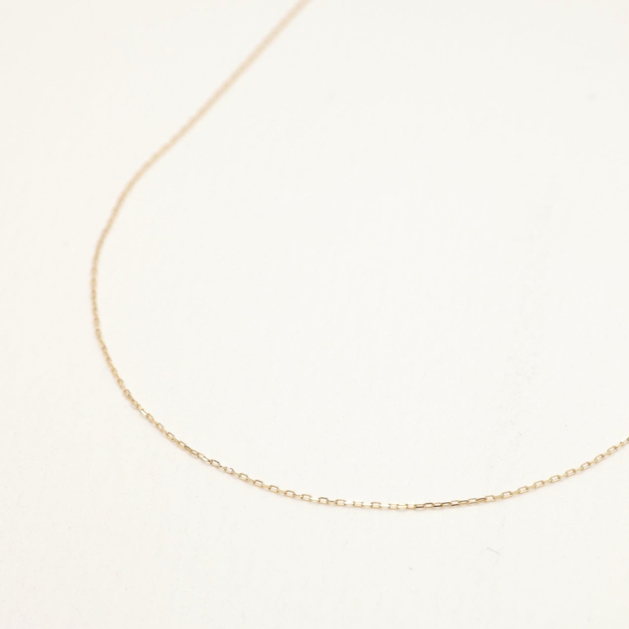The Édith Petite Chain Necklace in 10K gold displayed in a looped arrangement, highlighting its refined minimal design.