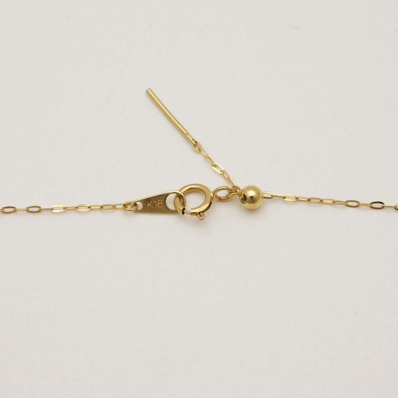 Émilie Chain Necklace in 18K gold laid in a soft curve, showing its adjustable sliding clasp detail.