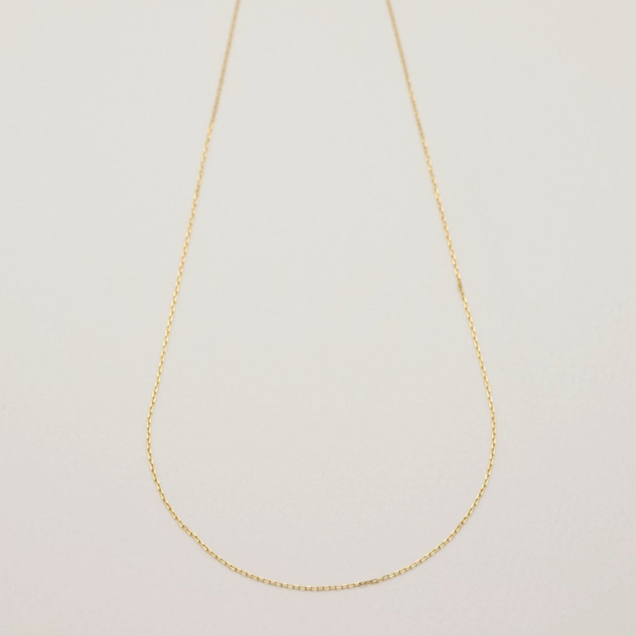 Minimalist product shot of the Émilie Chain Necklace in 18K gold, displayed flat to highlight chain style and length.