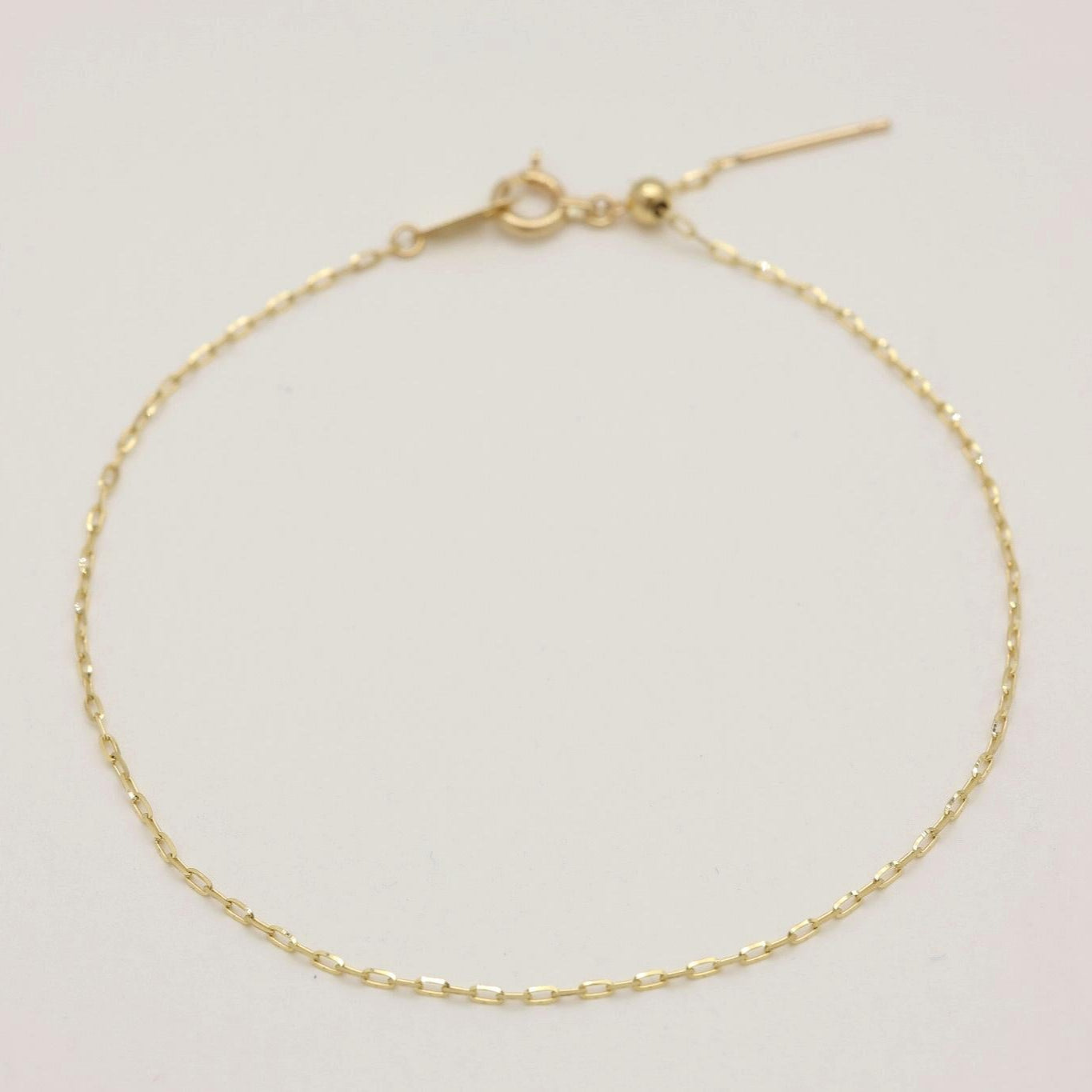 A 10K yellow gold bracelet with fine oval links, displayed laid flat with adjustable clasp in view.