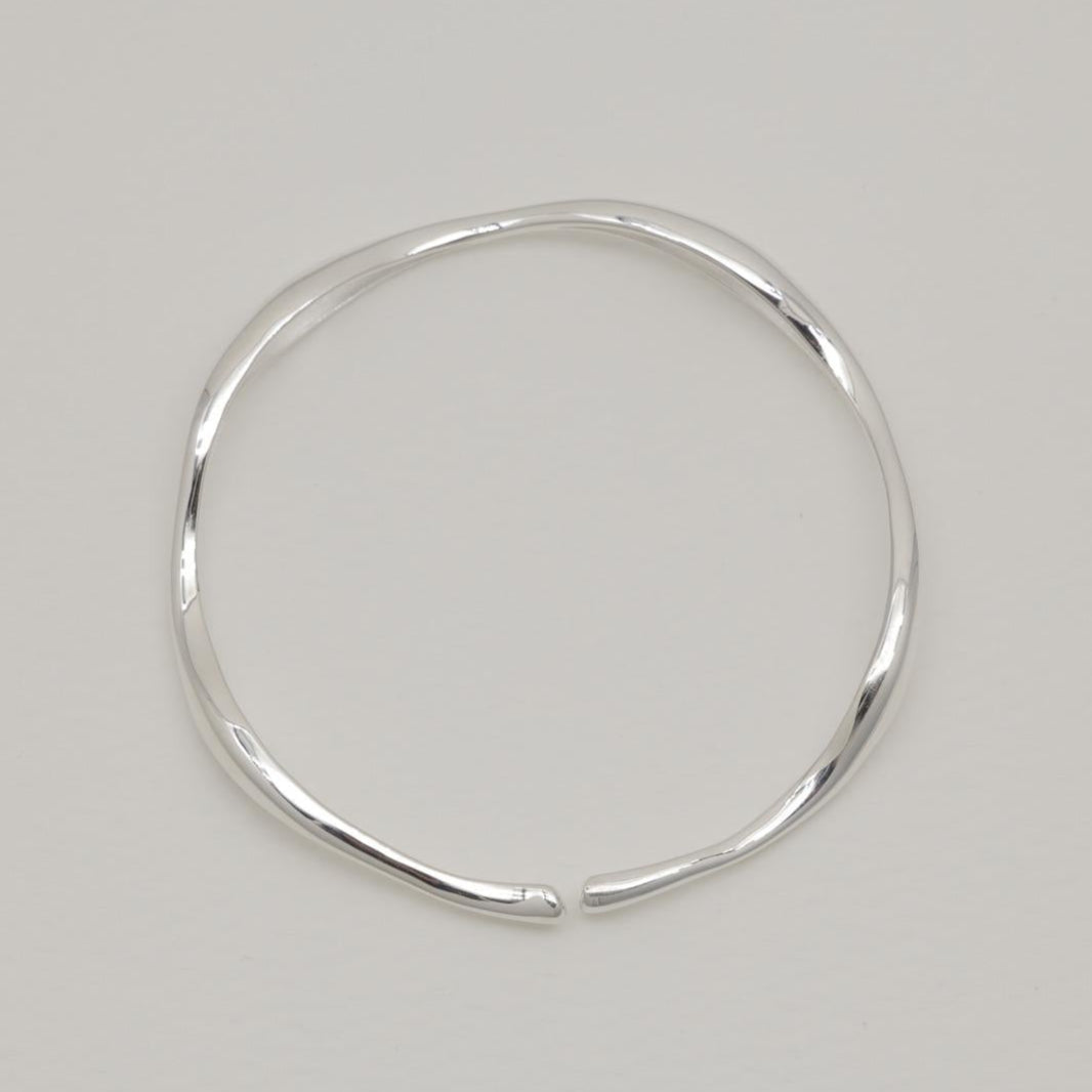 Image 1: Sculptural sterling silver cuff bracelet with fluid curves, displayed on a soft white background.