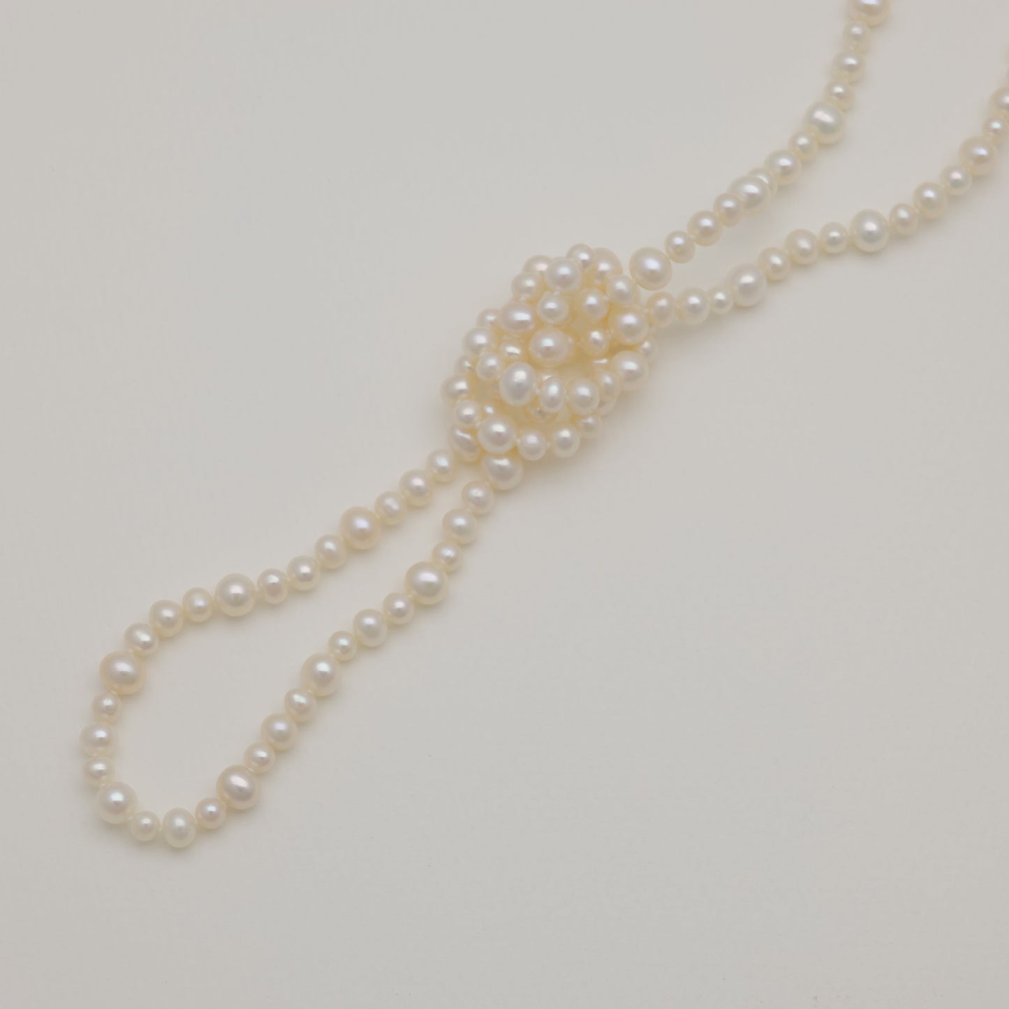 Freshwater pearl long necklace with natural luster, styled on cream background.