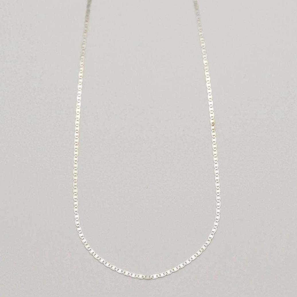 A full-length view of the Aliane Chain Necklace in 925 sterling silver, laid in a soft curve against a neutral backdrop.