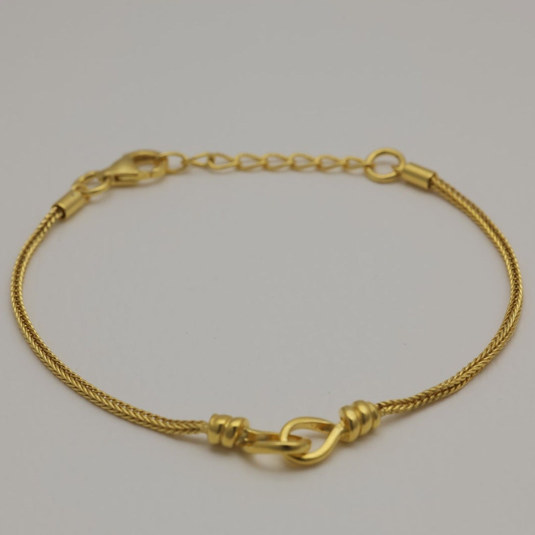Gold vermeil bracelet with braided chain and loop detail, laid flat and in a circular shape.