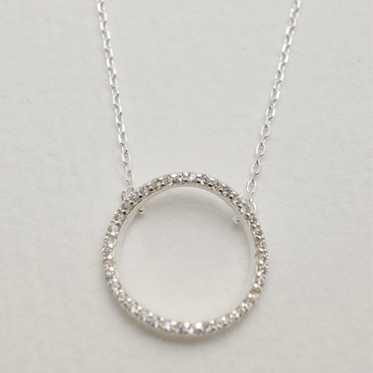 Detailed close-up of the pavé circle pendant showing fine cubic zirconia stones set into polished sterling silver.