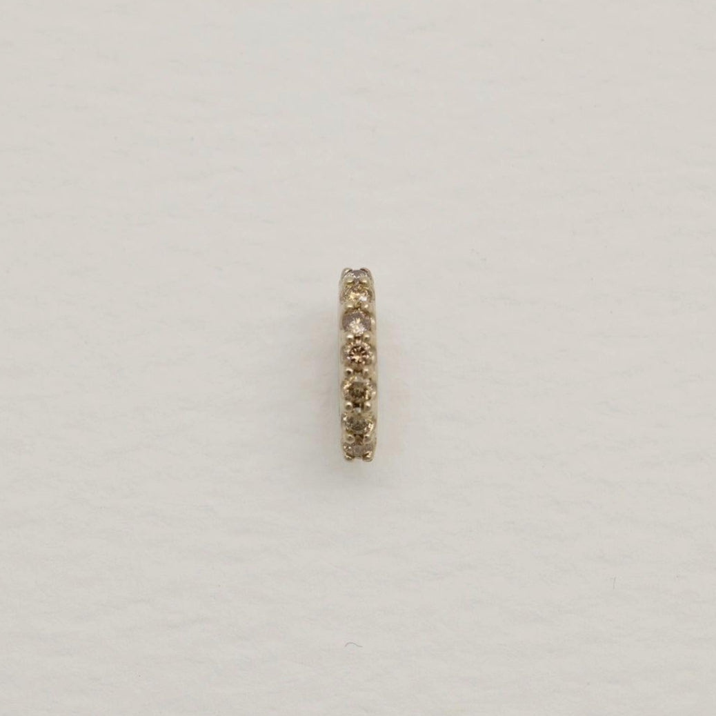 14K gold oval charm with natural pavé diamonds along one edge, photographed on a soft white background.