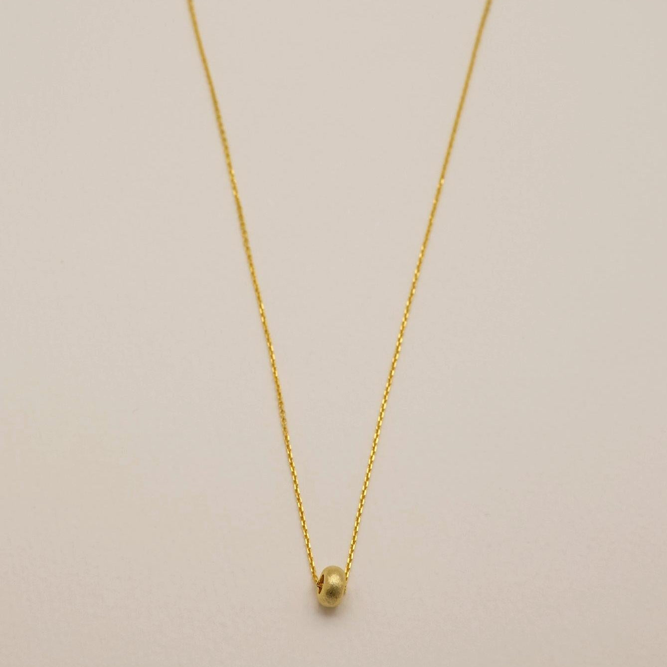 Full view of gold vermeil Noémie necklace with matte donut bead on silver chain