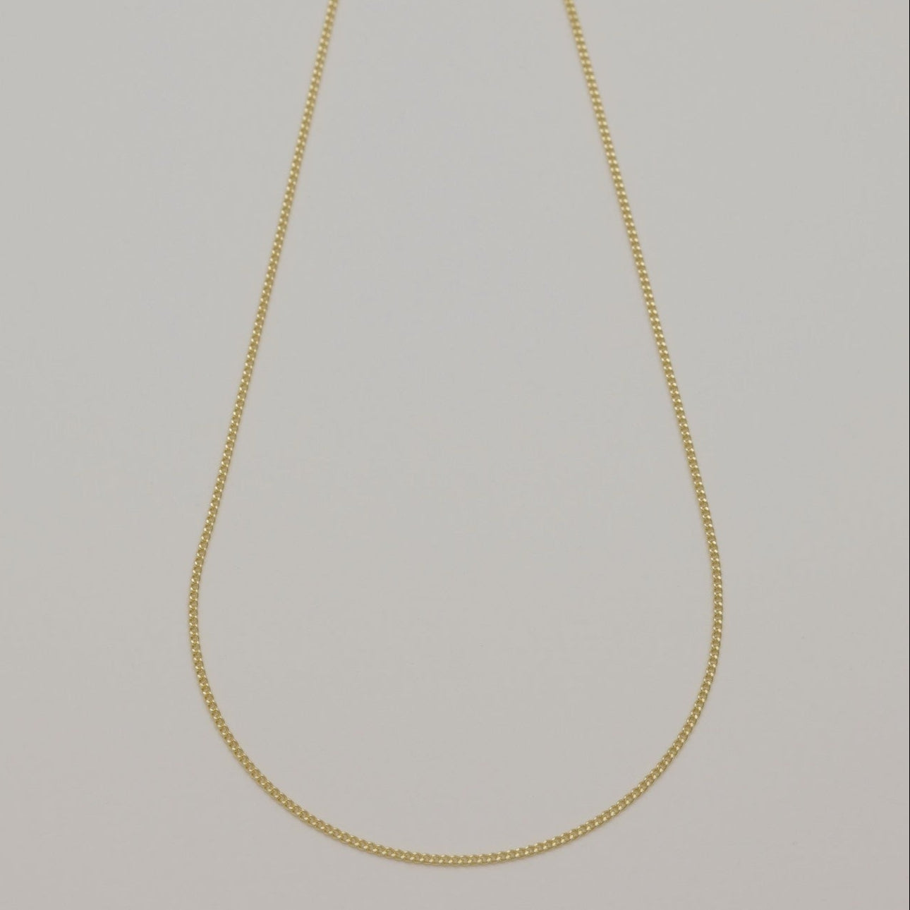 Full view of Amélia Chain Necklace in 14K gold laid flat against a neutral background