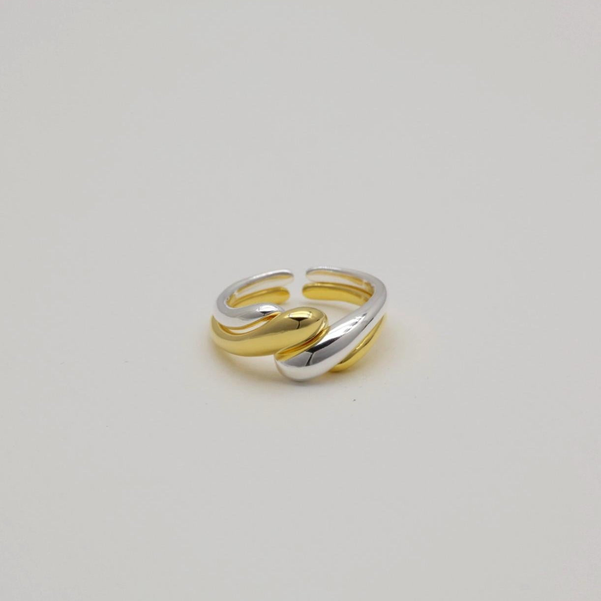 Silver and gold crossover rings displayed flat on a light backdrop