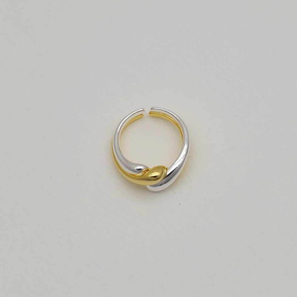 Silver and gold crossover rings displayed flat on a light backdrop