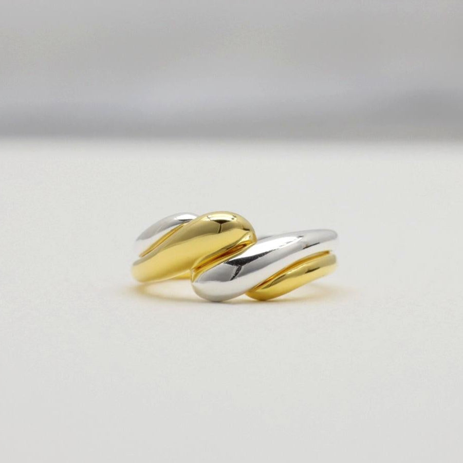 Silver and gold crossover rings displayed flat on a light backdrop