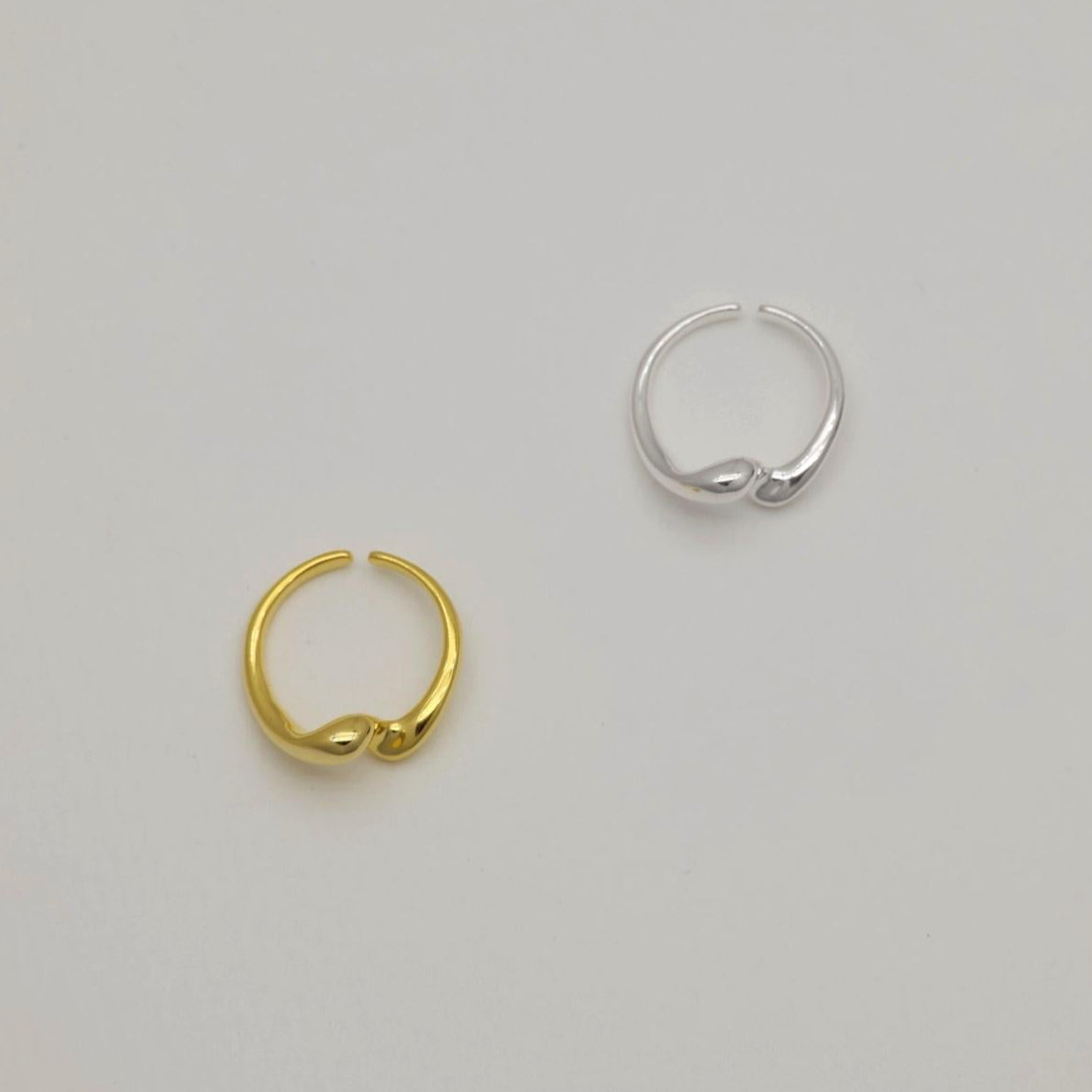 Silver and gold crossover rings displayed flat on a light backdrop