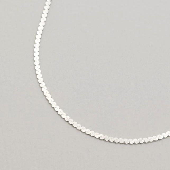 A sterling silver flat chain necklace with bold interlinked discs and a polished finish, shown in close-up and full length on a neutral background.