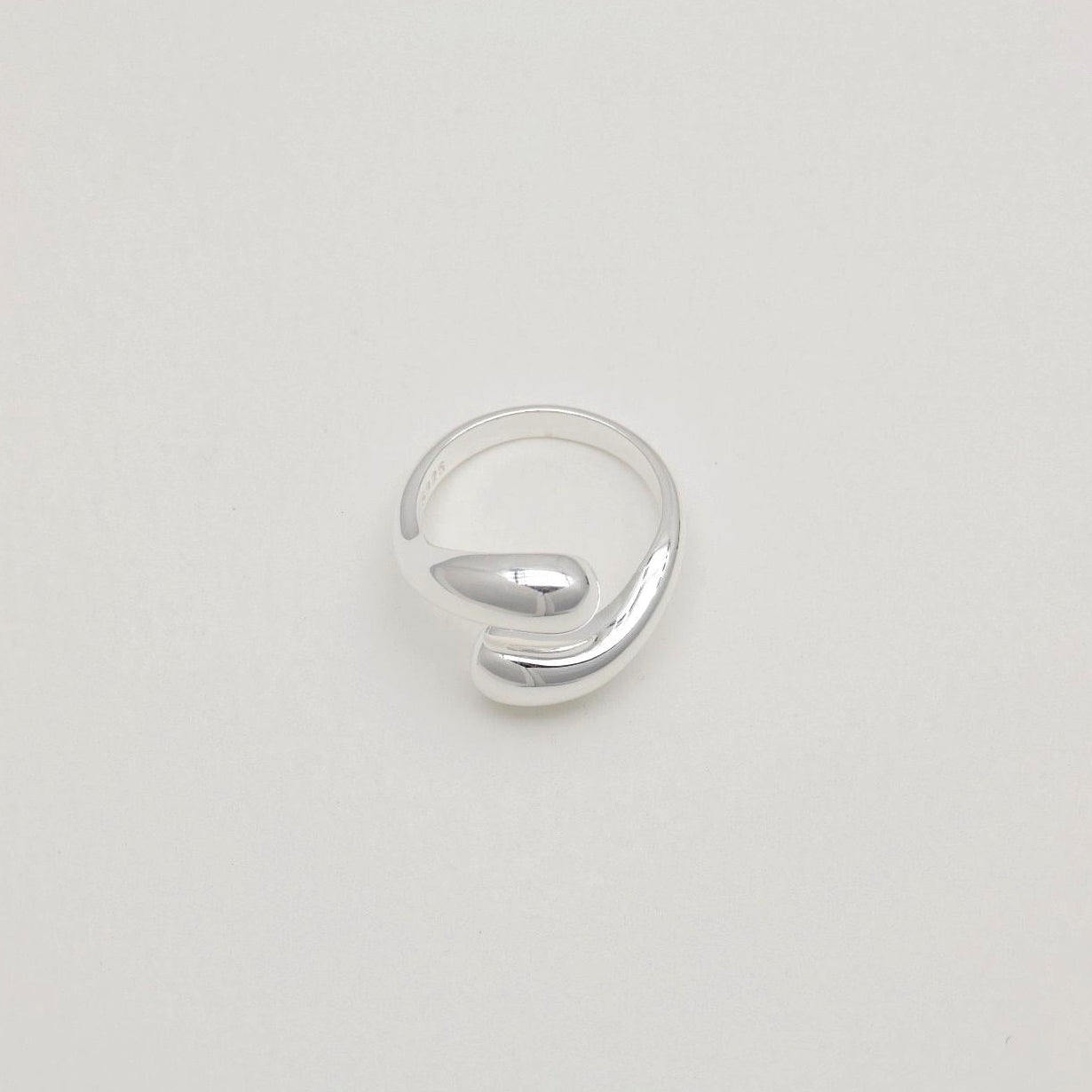 Sculptural sterling silver ring with teardrop-like ends and a polished adjustable wrap design.