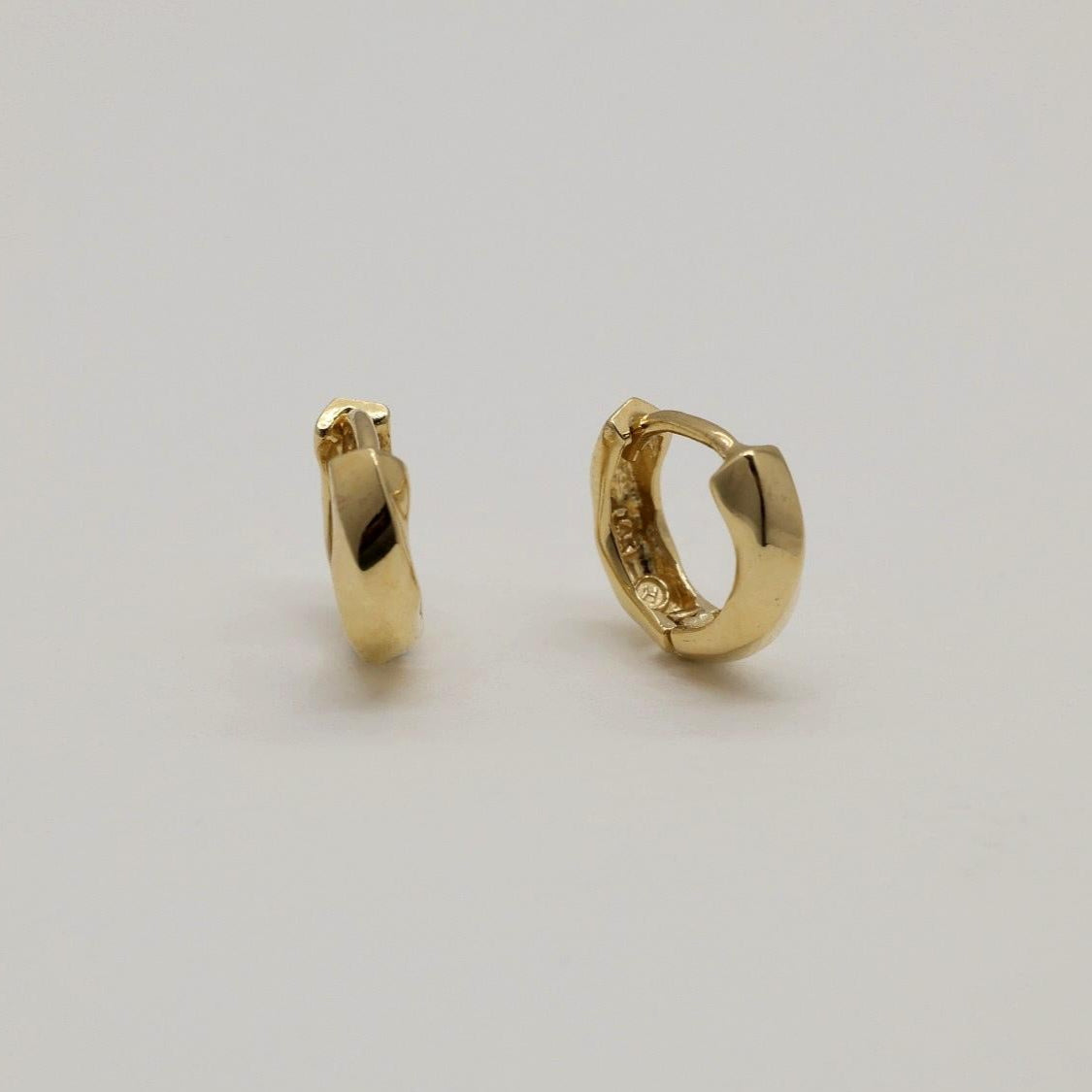 14K gold huggie earrings with softly curved silhouette, photographed on a white background.