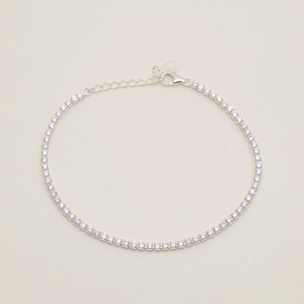 A sterling silver adjustable tennis bracelet with brilliant cubic zirconia, set in a polished prong setting, displayed elegantly on a white surface.