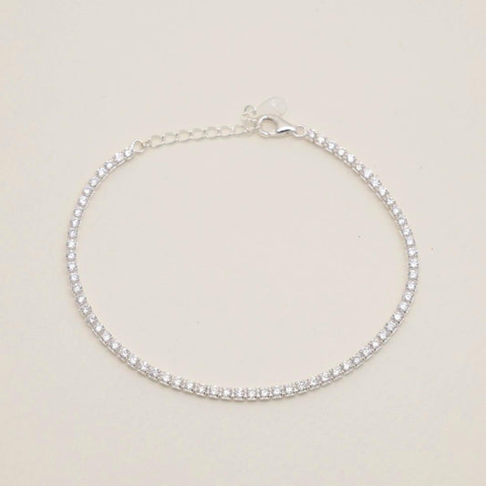A sterling silver adjustable tennis bracelet with brilliant cubic zirconia, set in a polished prong setting, displayed elegantly on a white surface.