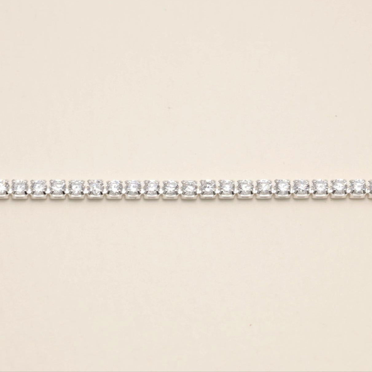 A sterling silver adjustable tennis bracelet with brilliant cubic zirconia, set in a polished prong setting, displayed elegantly on a white surface.