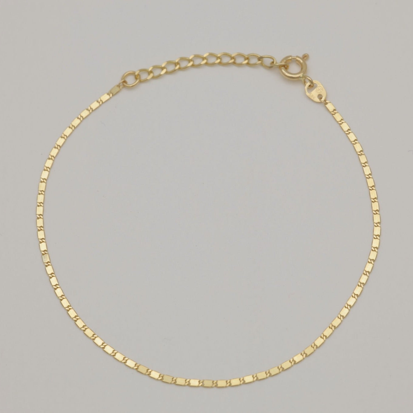 Elegant 14K gold bracelet with classic chain design, laid flat on a neutral background.
