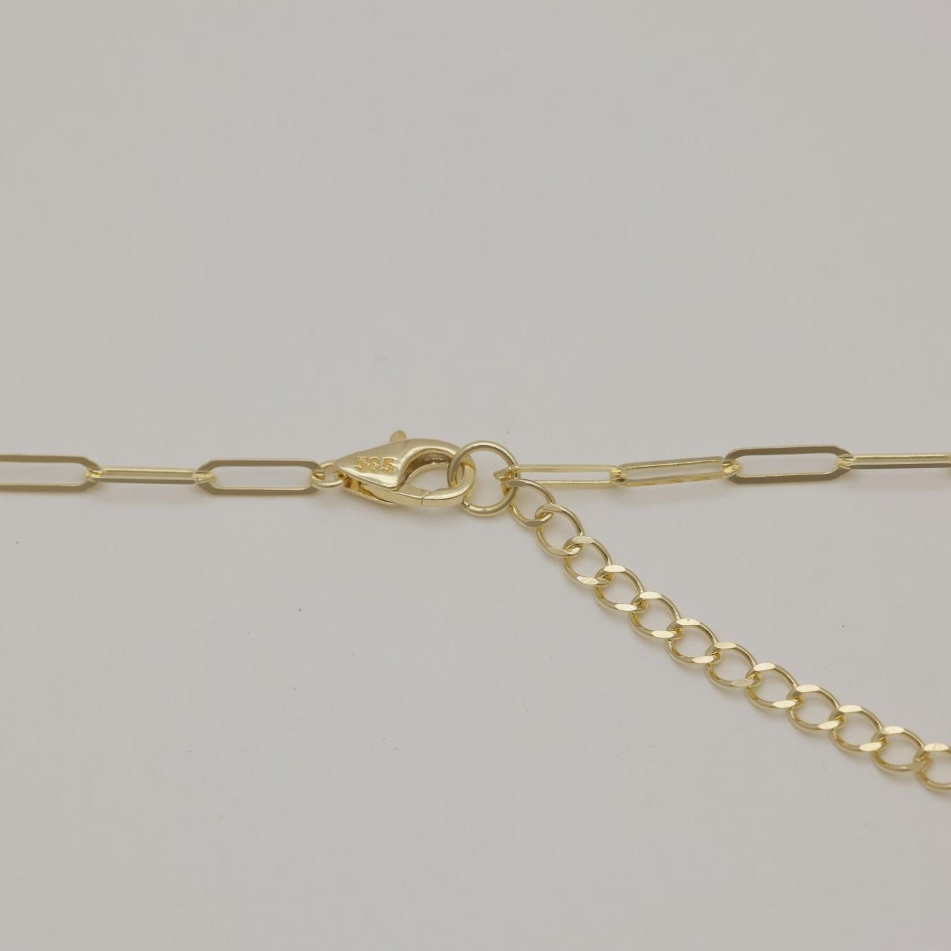 Minimalist 14K gold necklace styled in a subtle loop on neutral surface