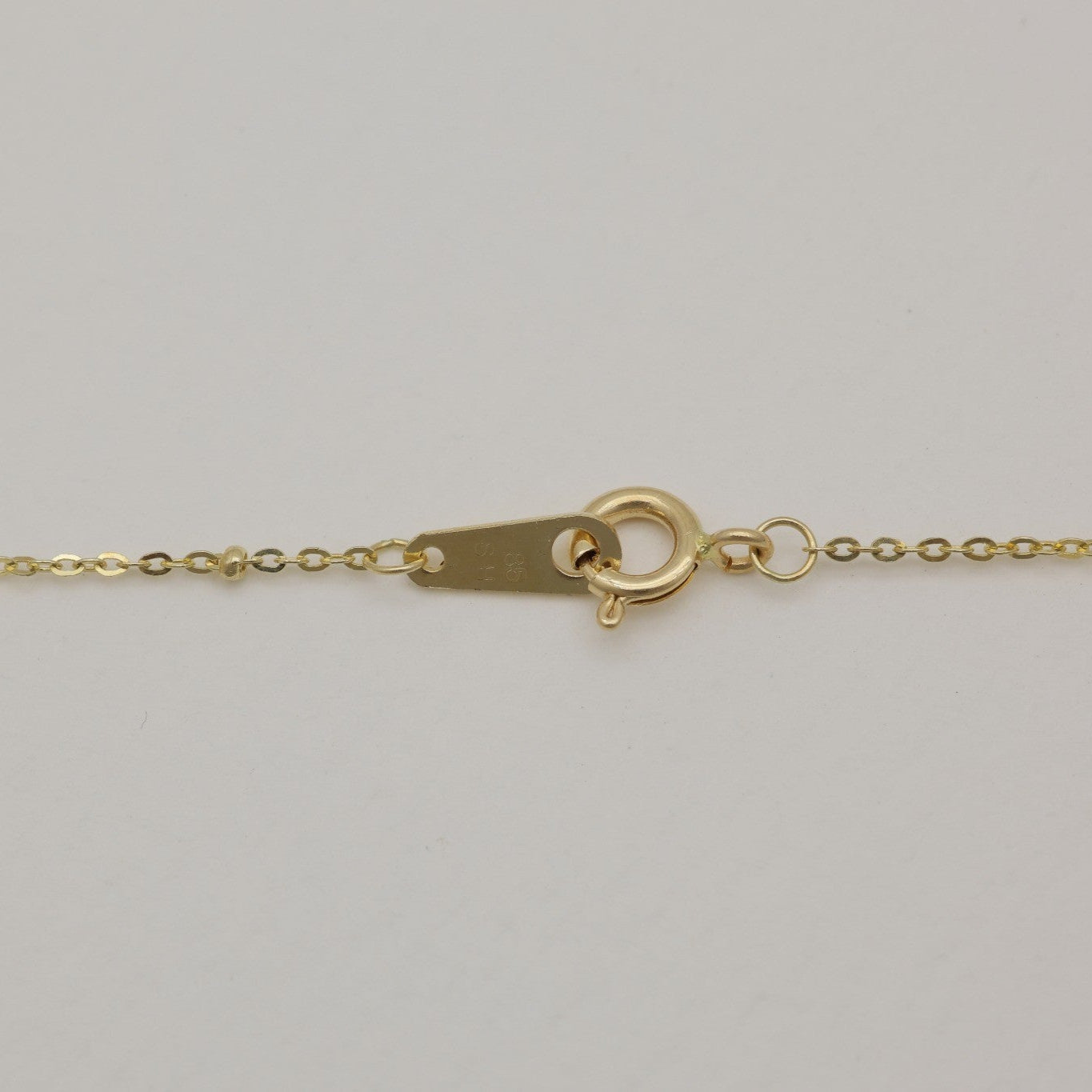 Close-up of spring clasp and bead detail on fine 14K gold chain