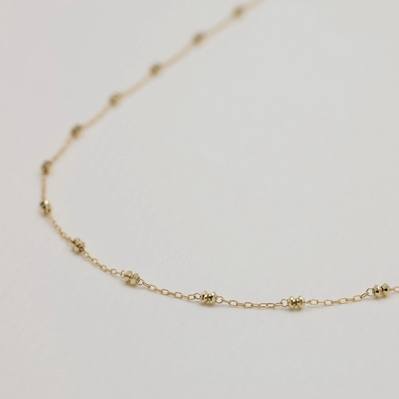 Close-up of beaded satellite chain links in polished 10K gold
