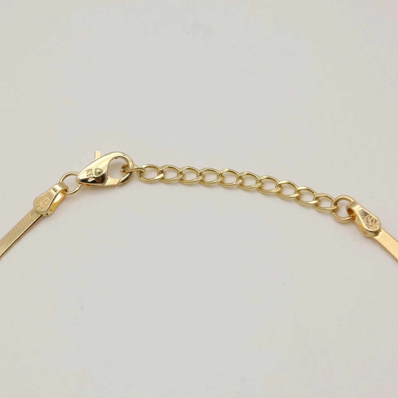 Flat-lay of 14K gold herringbone bracelet with reflective polished finish