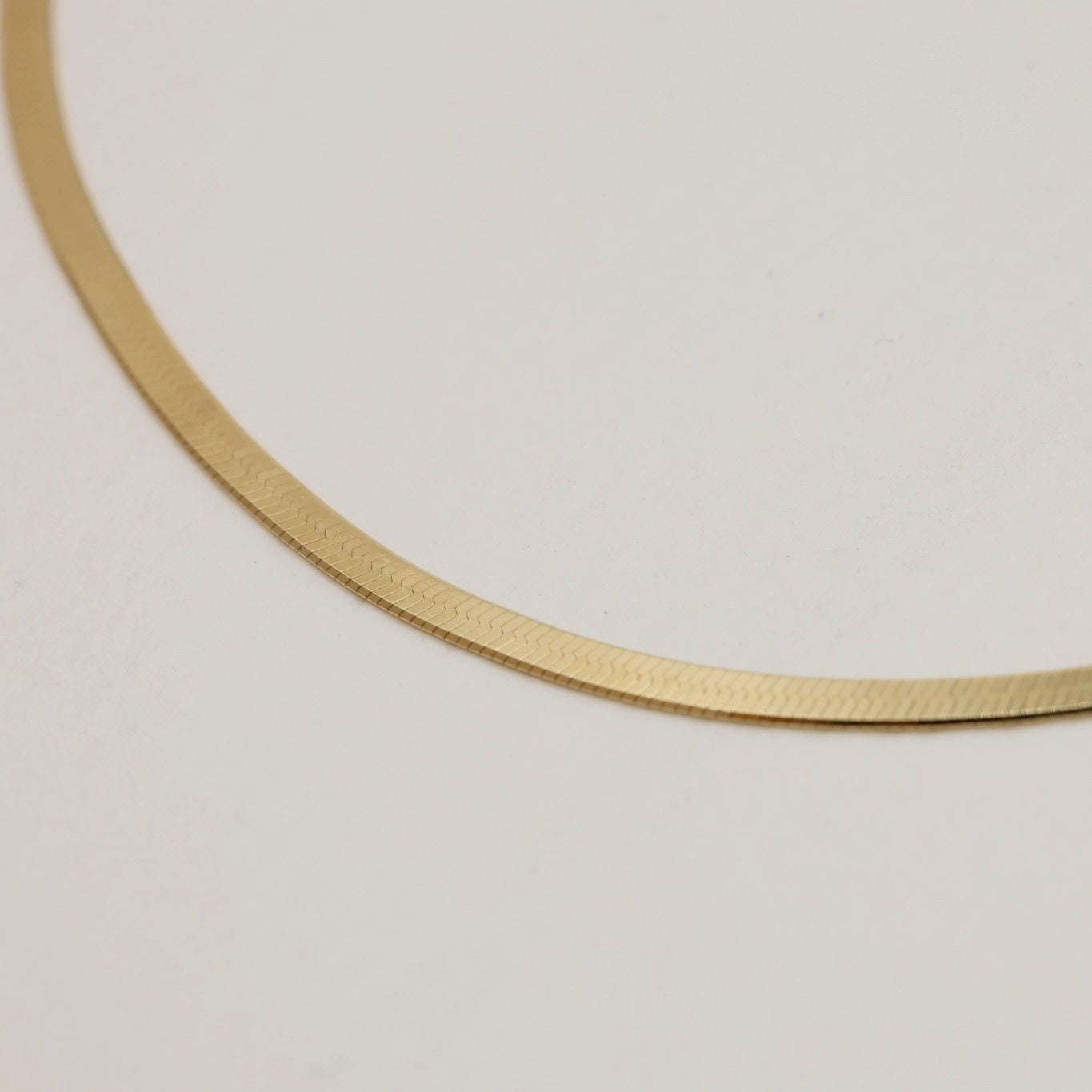Close-up of herringbone chain links showing sleek texture and gold sheen