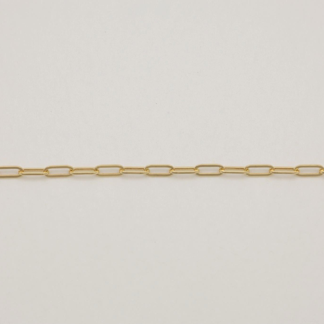 Flat lay of 18K gold paperclip chain against light background.