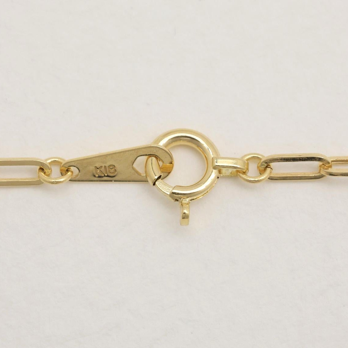 Spring clasp detail with “K18” gold marking and tag.
