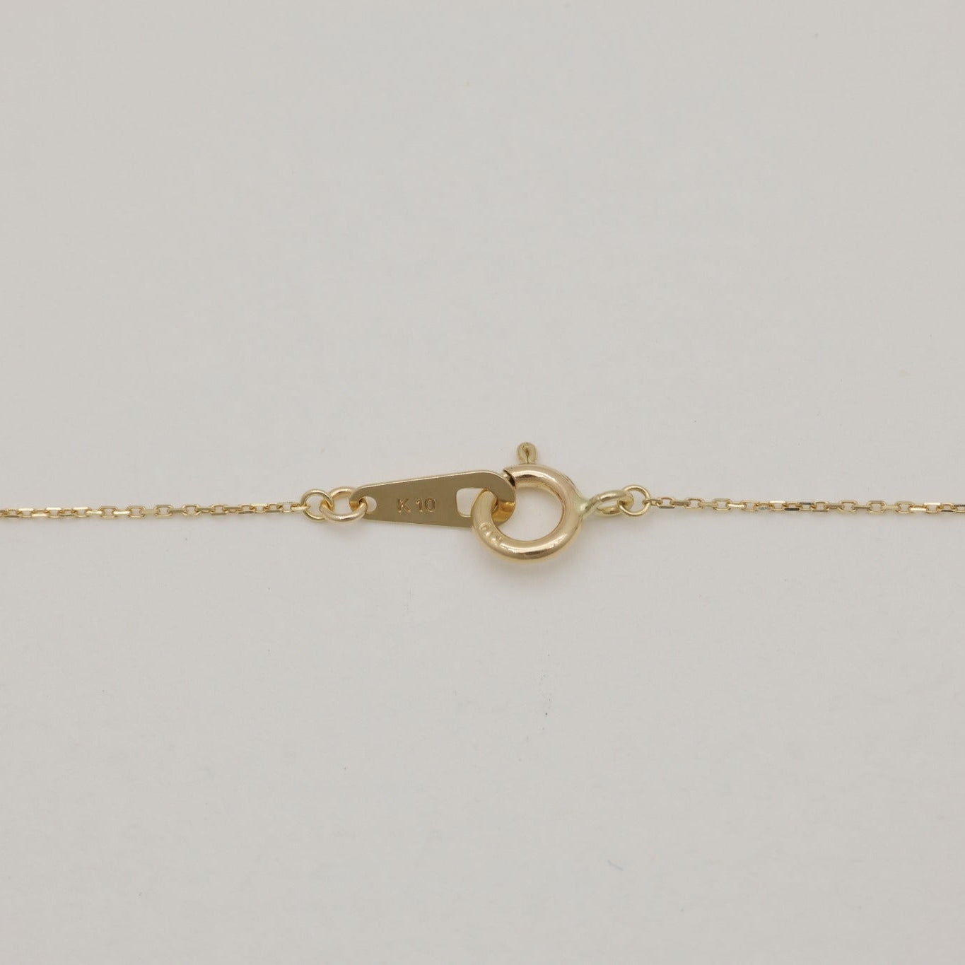 Close-up of a delicate 10K gold chain with spring ring clasp, engraved with K10 hallmark.