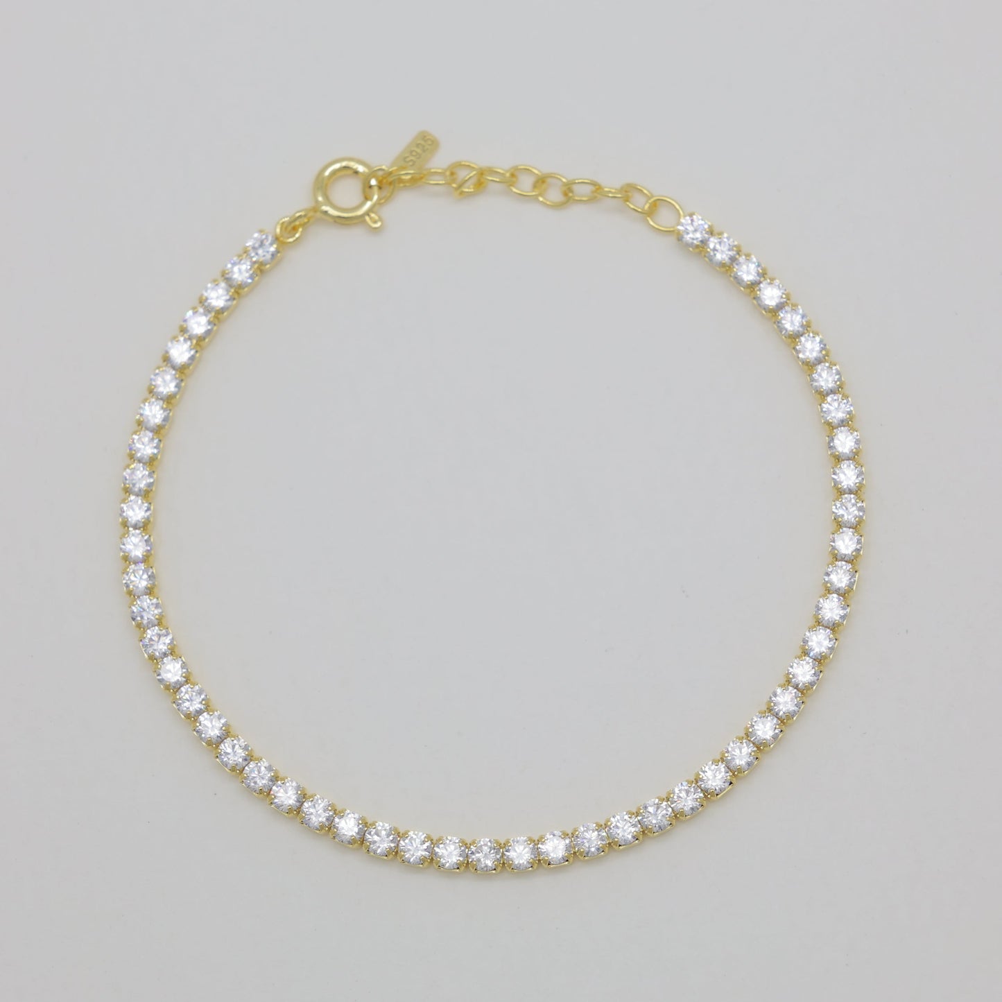 Gold bracelet with clear stones on a gray background