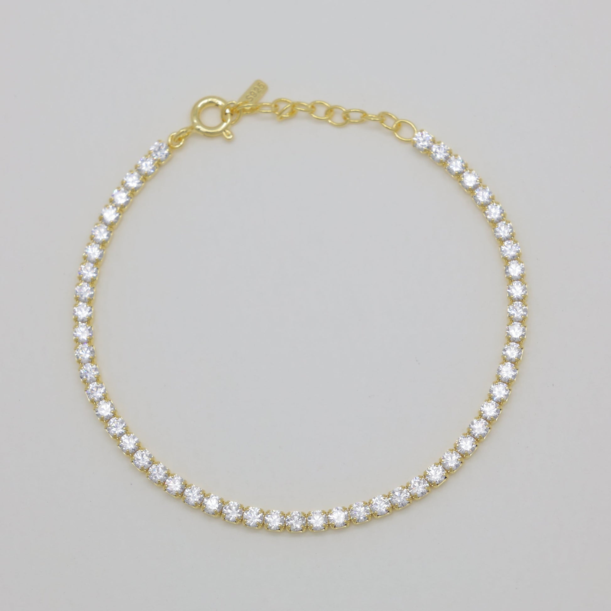 Gold bracelet with clear stones on a gray background