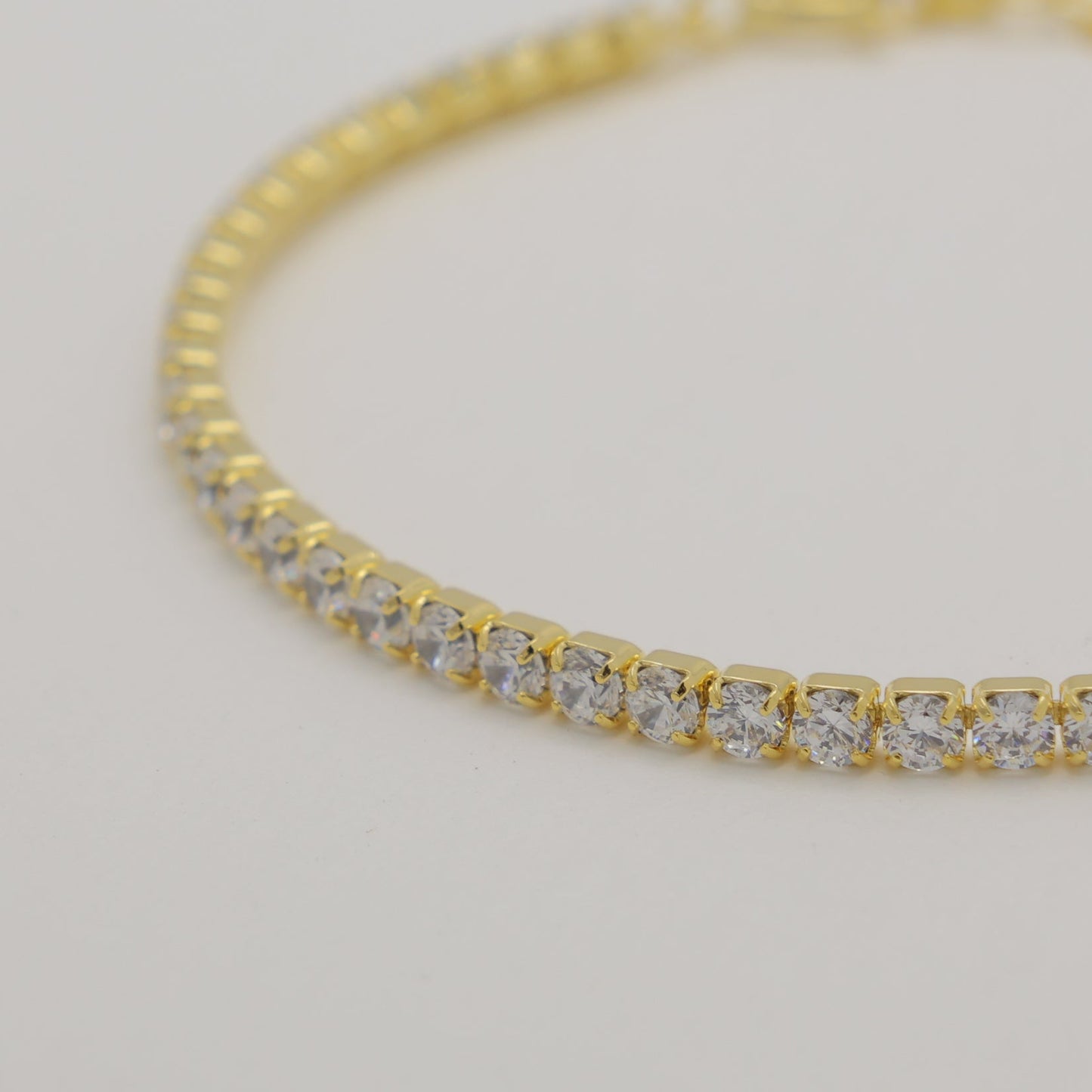 Gold bracelet with diamonds on a light gray background