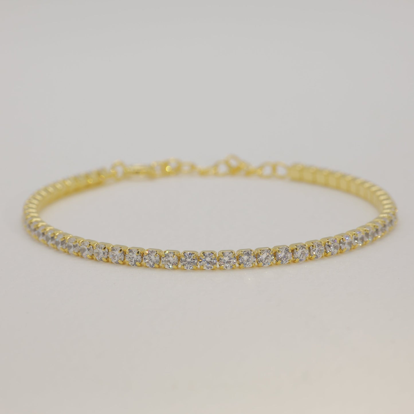 Gold bracelet with diamonds on a light gray background