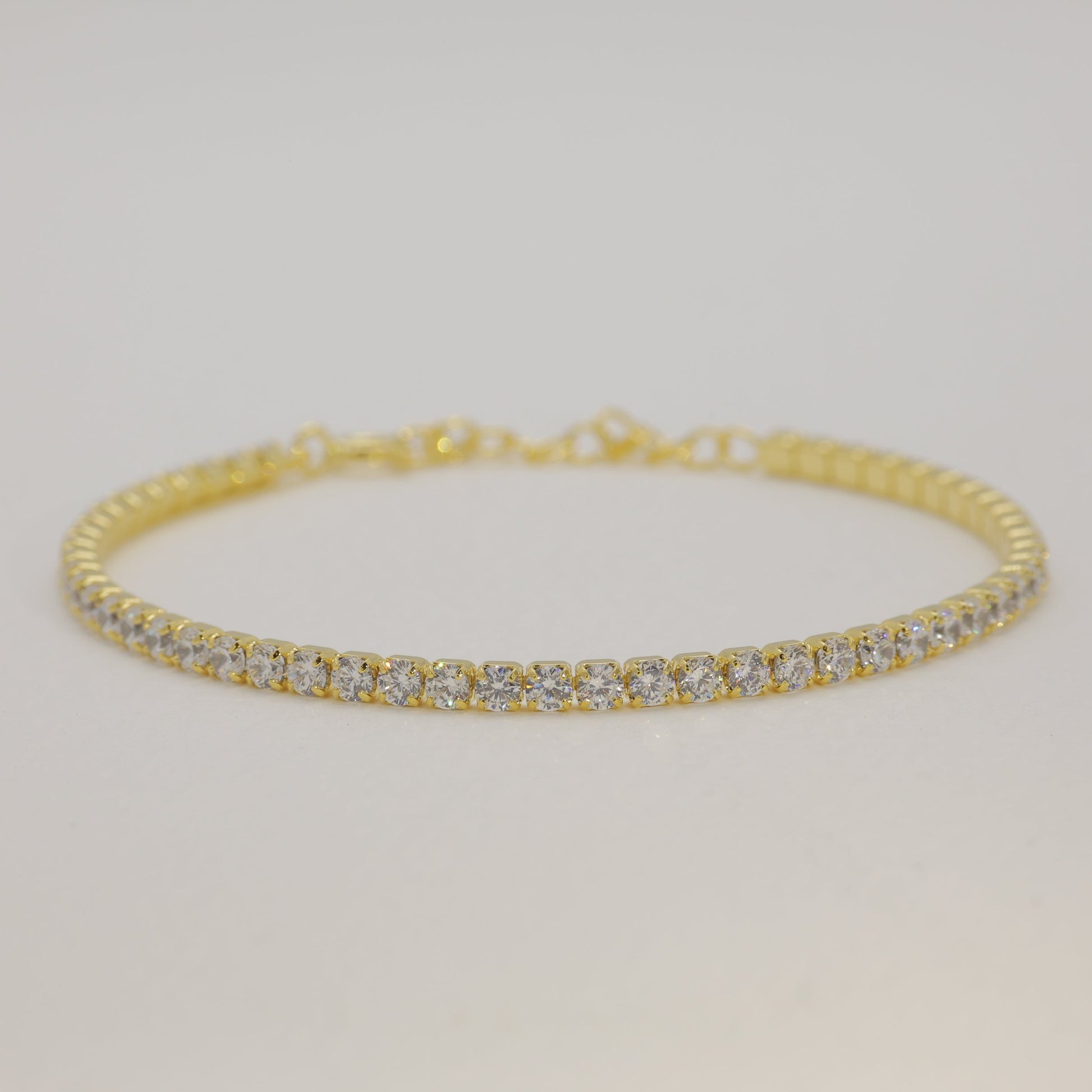 Gold bracelet with diamonds on a light gray background