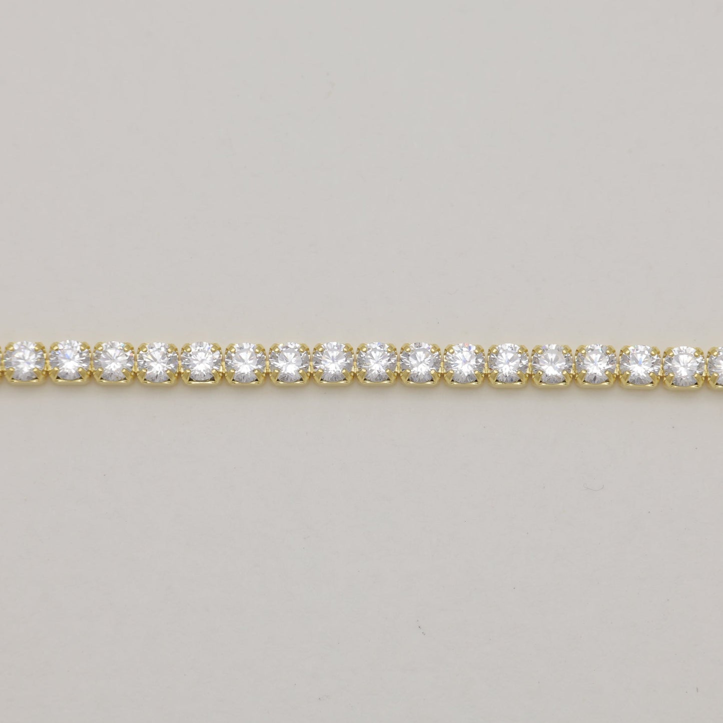 Gold bracelet with clear stones on a light gray background