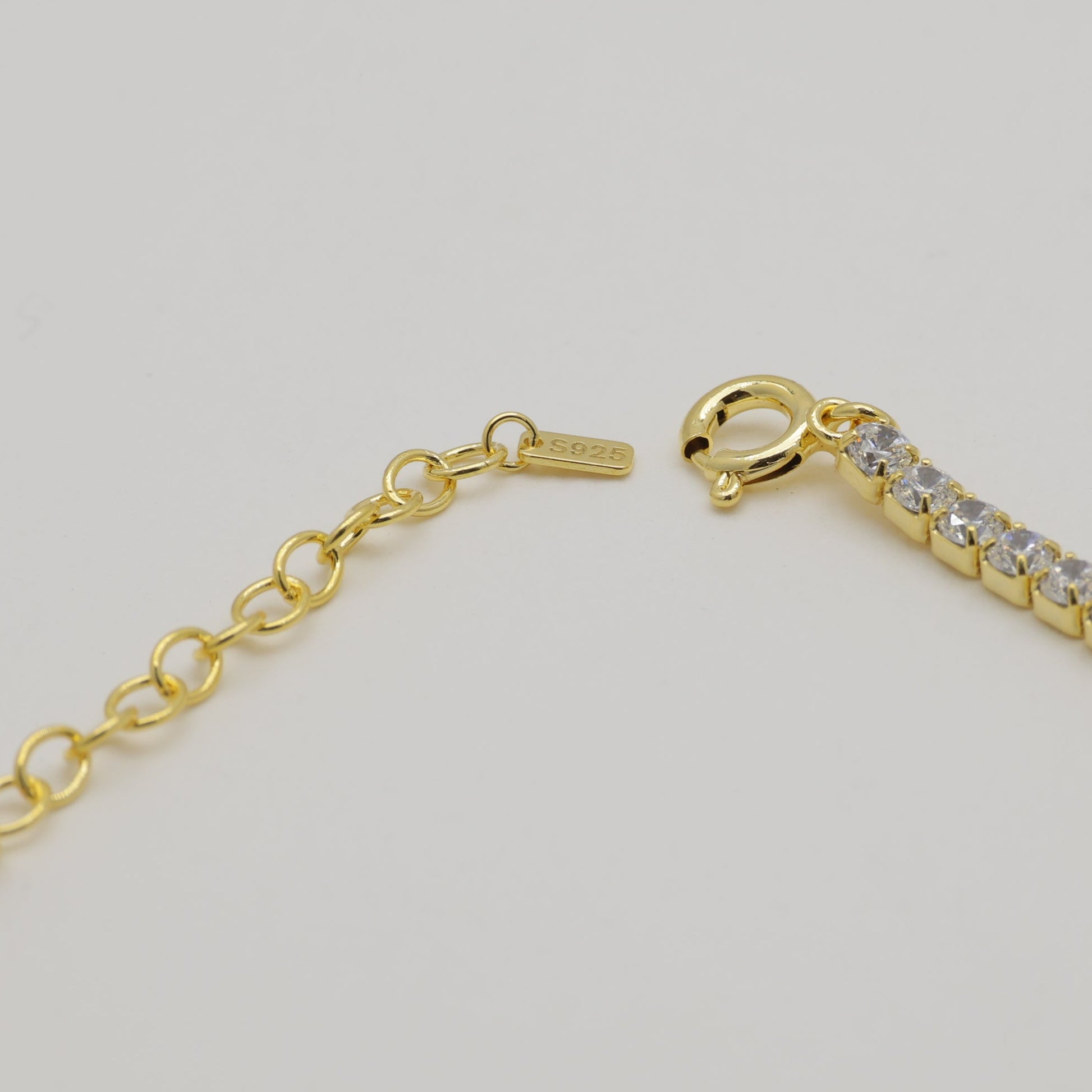 Gold bracelet with clear stones on a light gray background