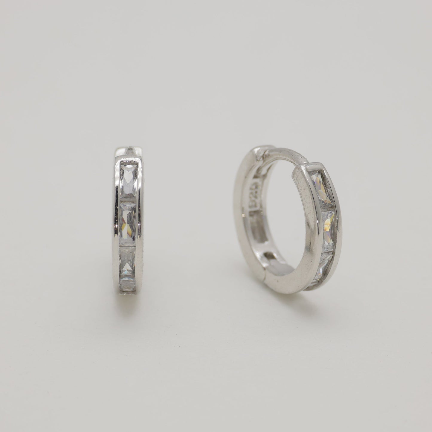 Two silver hoop earrings on a light gray background